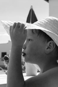 Side view of boy looking away while holding hat