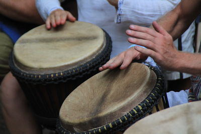 Midsection of people playing drum