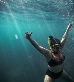 Mid adult woman with arms raised swimming in pool