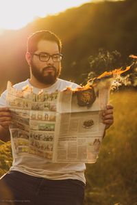 Man reading burning newspaper outdoors