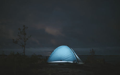 Lonely luminous tent in a remote location on a cloudy night. themes of tourism and active lifestyle.