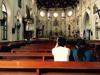 Rear view of women sitting on bench at temple