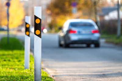 Poles at the traffic safety speed bumps in residential area, blurred background with a car, closeup