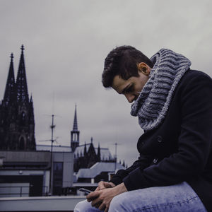 Close-up of a man with clock tower against sky
