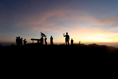 Silhouette people standing on shore against sky during sunset