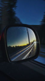 Close-up of side-view mirror against sky