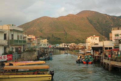 Boats moored in river by mountains against sky