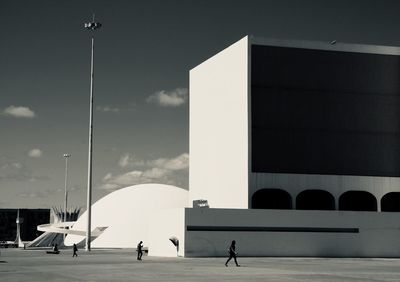 People walking on street by buildings against sky