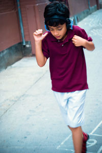 Boy wearing headphones while walking on road in city