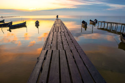 Pier over sea against sky during sunset