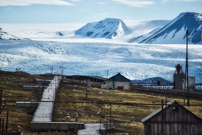 Snow covered houses by mountain against sky