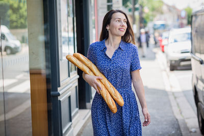 Young woman buying a french baguette