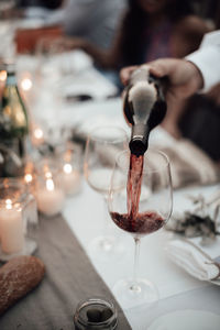 Close-up of hand pouring wine in glass on table