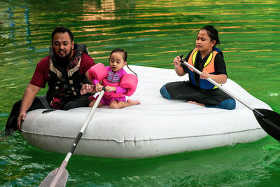 Happy friends sitting on boat in lake