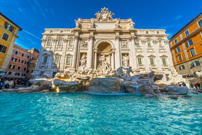 Trevi fountain outside historic building against blue sky