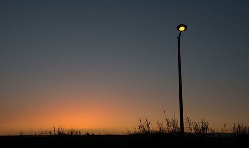 Silhouette street light on field during sunset