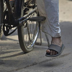 Low section of man standing on bicycle in city