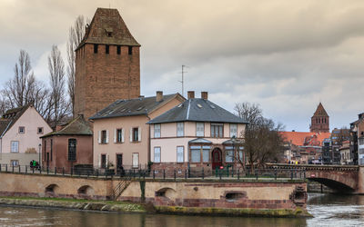 Arch bridge over river by buildings against sky