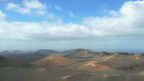 Scenic view of desert against cloudy sky