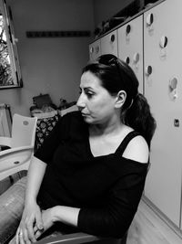 Thoughtful woman sitting on chair at home