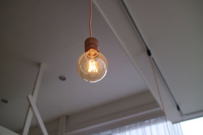 Low angle view of illuminated pendant light hanging from ceiling