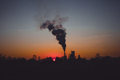 Smoke emitting from chimney against sky at sunset