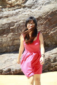 Beautiful young woman standing against stone wall