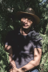 Portrait of young man standing against trees in forest