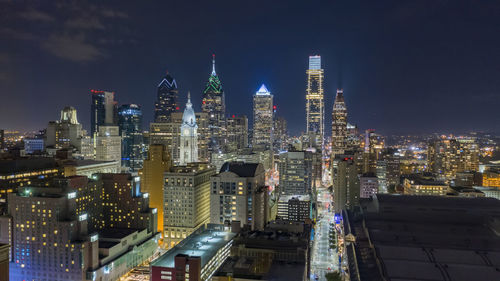 Illuminated buildings in city against sky at night