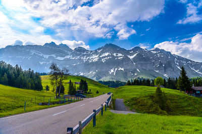 Road amidst green landscape against sky