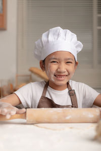 Close-up asian little girl using a rolling pin kneading the dough for making homemade