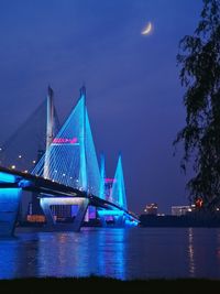 Illuminated bridge over river at night