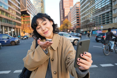 Young woman using mobile phone in city