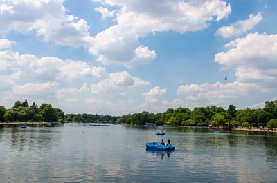 People rowing boat in river against sky