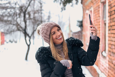 Portrait of smiling young woman standing in snow