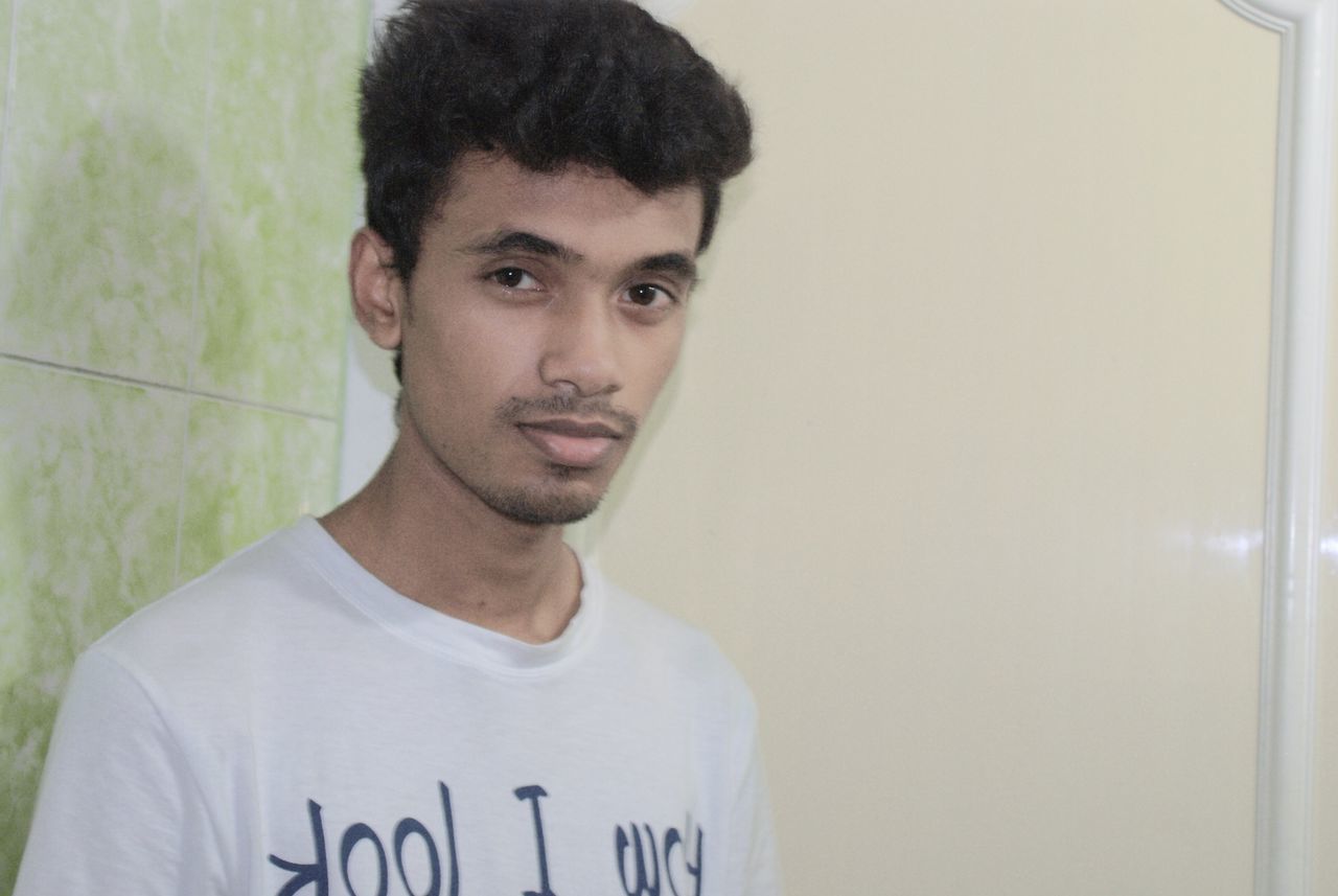 indoors, lifestyles, young adult, person, portrait, looking at camera, front view, young men, casual clothing, leisure activity, headshot, waist up, wall - building feature, standing, communication, copy space, close-up, confidence