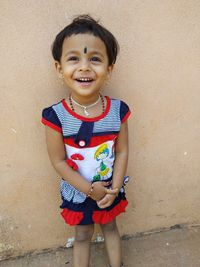 Portrait of smiling girl standing against wall