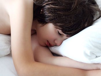 High angle view of shirtless boy sleeping on bed