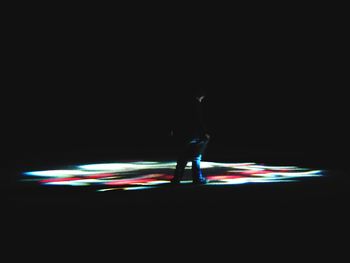 Man standing against illuminated lights at night