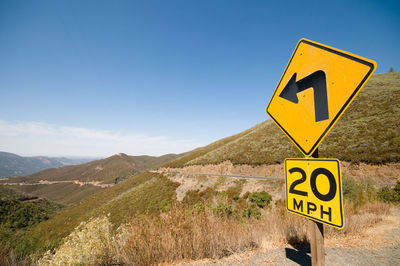 Road sign by mountains against sky