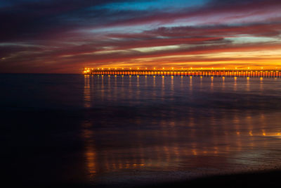 Scenic view of sea against cloudy sky at sunset