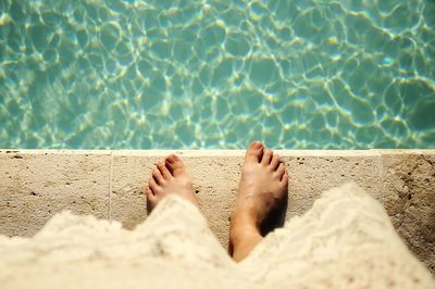 Low section of woman standing by swimming pool