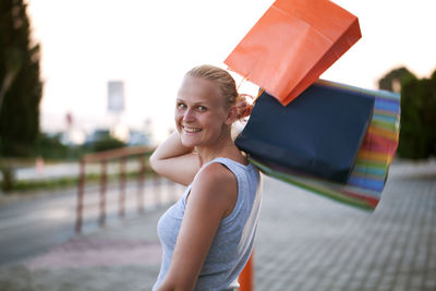 Portrait of happy young woman with shopping bags on street