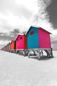 Multi colored deck chairs on beach against sky