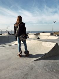 Rear view of woman with skateboard at skateboard park