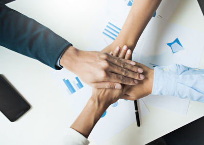 High angle view of business people stacking hands at desk in office