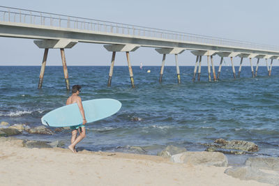 Shirtless man with surfboard at beach