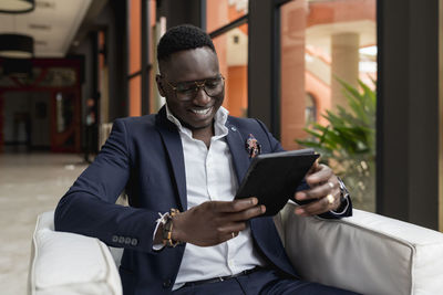 Smiling male entrepreneur using digital tablet while sitting in hotel lobby