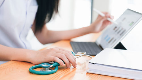 Midsection of woman using smart phone on table