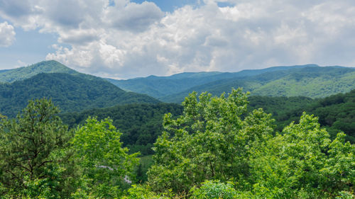 Scenic view of green mountains against cloudy sky